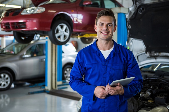 portrait of mechanic holding digital tablet at repair garage
